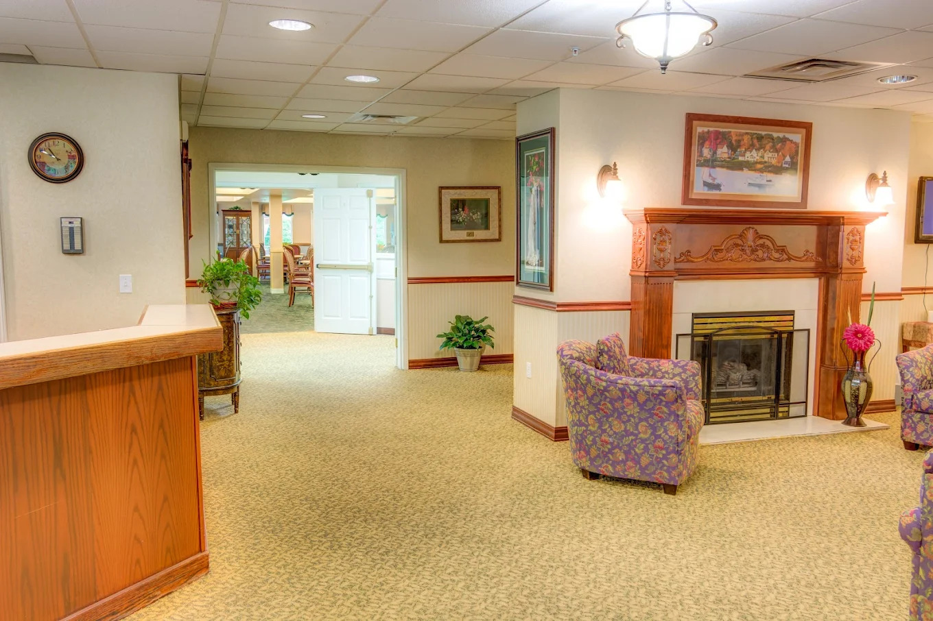 Sitting area off the entry with armchairs gathered around a cherry fireplace mantel